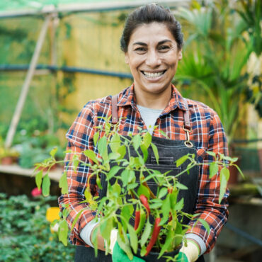 Happy latin woman working inside greenhouse garden – Nursery and spring concept – Focus on face